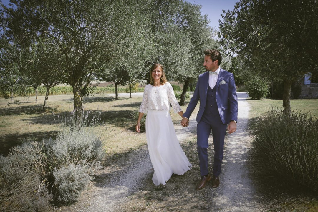 Eysines - Couple de jeunes mariés marchant le long d'un chemin entouré d'oliviers